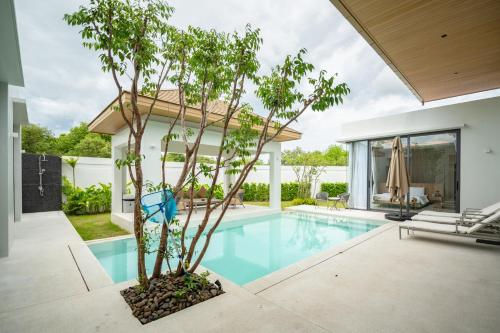 a pool with a tree next to a house at Mouana Residence Song Khun Chalong 5-bedroom Pool Villa 89-11 in Chalong 