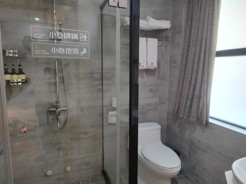 a bathroom with a toilet and a shower with a sign at Qingshan Yuandai Boutique Homestay Yangshuo in Yangshuo