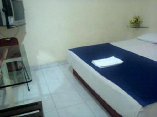 a room with a bed with a blue blanket and a tv at Mitra Hotel Yogyakarta in Yogyakarta