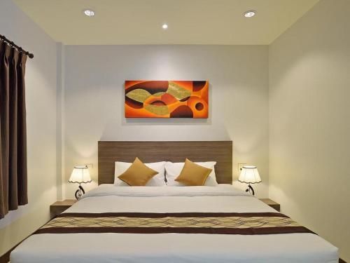 a bedroom with a large white bed with two lamps at The Rich Resort in Krabi town