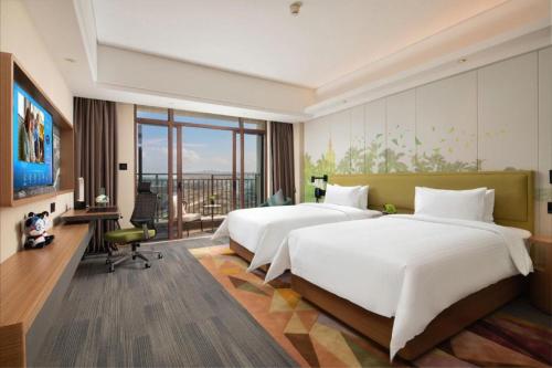 海口市にあるHampton by Hilton Nanhai Haikouのベッド2台と机があるホテルの部屋