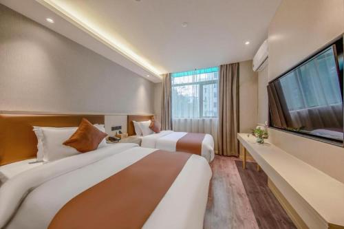 une chambre d'hôtel avec deux lits et une grande télévision dans l'établissement Gya Hotel Shanghai Long Distance Passenger Terminal Station, à Shanghai