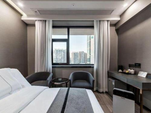 a bedroom with a bed and a desk and a window at Xiamen Dongchen Hotel in Xiamen