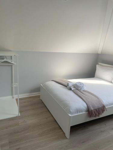 a white bedroom with a bed with white sheets at Modern and Accessible in Galway