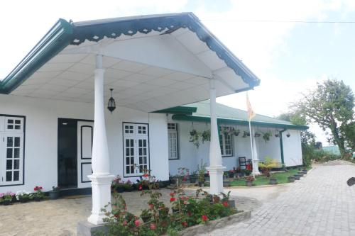 a white house with awning and flowers in front at Silver Meir Bungalow in Nuwara Eliya