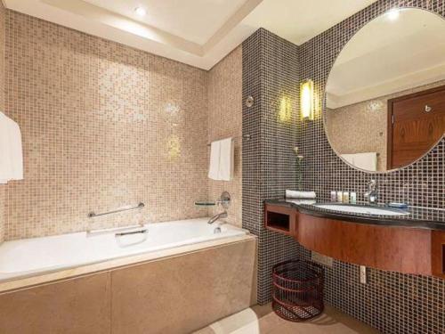 a bathroom with a tub and a sink and a mirror at Kunshan Newport Hotel in Suzhou