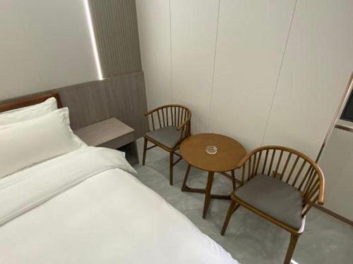 a bedroom with a bed and two chairs and a table at Movie Star Hotel in Guangzhou