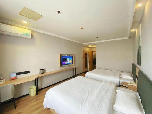 a hospital room with two beds and a tv at GreenTree Inn Taizhou New District Hospital of Renmin Hospital Mingliu Express Hotel in Jiuligou