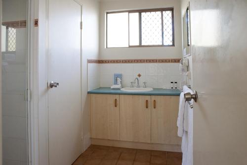a bathroom with a sink, mirror, and tub at Kondari Hotel in Hervey Bay