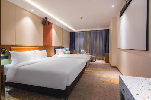 une chambre d'hôtel avec deux lits et un écran de projection dans l'établissement Gtel Rock City Qingdao Hotel, à Laoshan