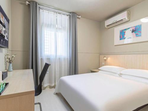 a bedroom with a white bed and a desk and a window at Jinjiang Inn Weihai High Speed Qingdao South Road in Weihai