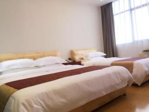two beds in a hotel room with a window at Jian Guo Grand Hotel in Vientiane