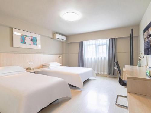 a hotel room with two beds and a window at Jinjiang Inn Weihai High Speed Qingdao South Road in Weihai