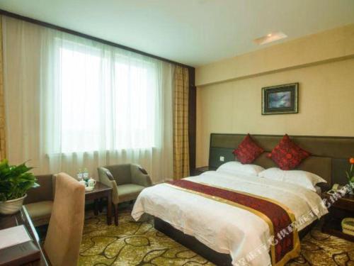 a hotel room with a bed and a table and a window at GreenTree Alliance Zhejiang Zhoushan Putuoshan Zhujiajian Scenic Spot Hotel in Zhoushan