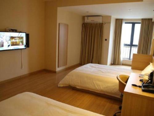 a hotel room with two beds and a flat screen tv at IU Hotel Chengdu High-Tech Zone Longhu Times Street in Chengdu
