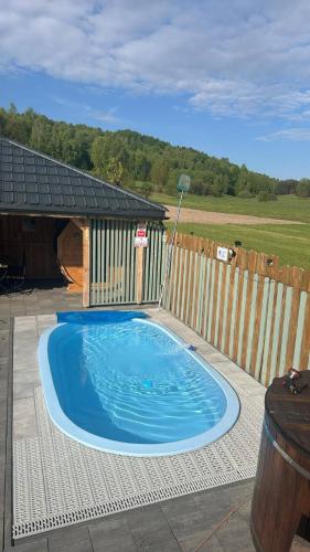 a small blue swimming pool in front of a wooden fence at Sielski Zaułek Guciów u Dorotki -Basen,Jacuzzi,Sauna in Guciów
