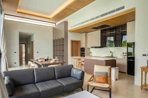a living room with a couch and a kitchen at Mouana Residence Song Khun Chalong 5-bedroom Pool Villa 89-11 in Chalong 