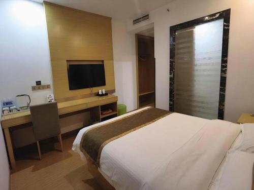 a bedroom with a bed and a desk with a television at GreenTree Inn Shanghai Fengxian District Xiaotang Metro Station in Shanghai