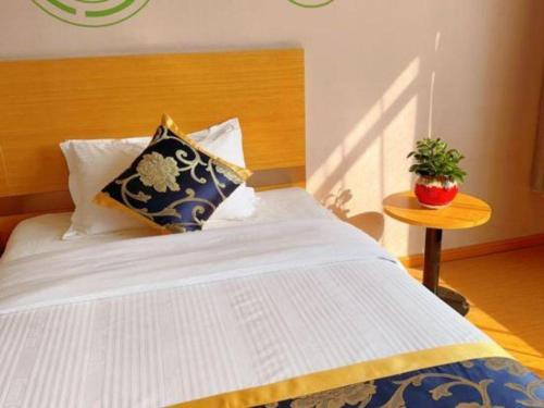 a bed with pillows and a table in a room at GreenTree Inn Shanghai Fengxian District Xiaotang Metro Station in Shanghai