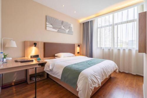 GreenTree Inn Wuxi Quanshan Center في ووشي: غرفة نوم بها سرير ومكتب ونافذة