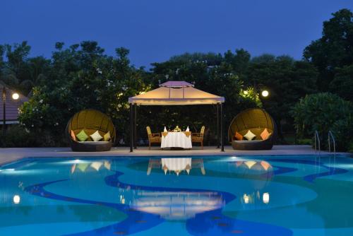 a table and a gazebo by a pool at night at Madhubhan Resort & Spa in Anand