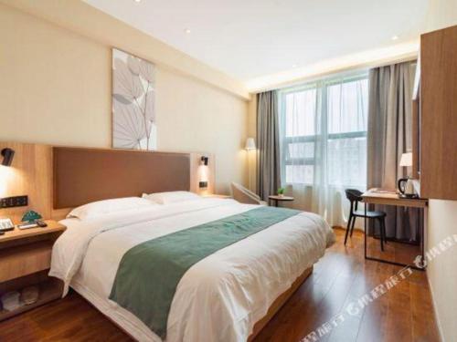 une chambre d'hôtel avec un grand lit et un bureau dans l'établissement GreenTree Inn Wuxi Quanshan Center, à Wuxi