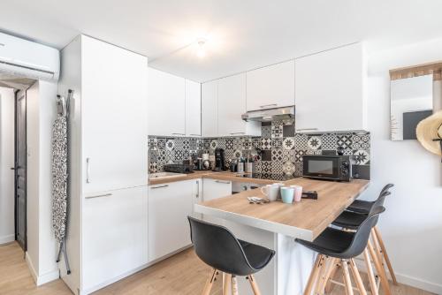 a kitchen with white cabinets and a wooden table and chairs at HOSSEA - Appartements Signature 10 min Océan in Saint-Vincent-de-Tyrosse