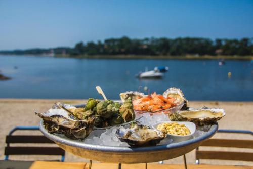 a plate of food on a table next to a beach at HOSSEA - Appartements Signature 10 min Océan in Saint-Vincent-de-Tyrosse