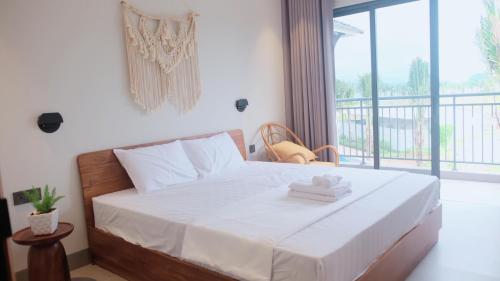 a bedroom with a bed with white sheets and a balcony at Villa V3N05A Sonasea Vân Đồn in Cái Rồng