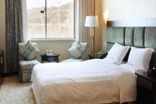 a hotel room with a large bed and a window at Golden Bay Hotel Weihai in Weihai
