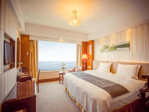 a hotel room with a bed and a large window at Golden Bay Hotel Weihai in Weihai