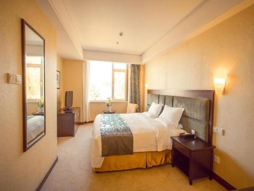 a hotel room with a bed and a large window at Golden Bay Hotel Weihai in Weihai