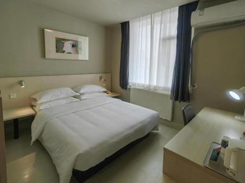 a bedroom with a large white bed and a desk at Jinjiang Inn Qingdao International Exhibition Center Haier Road in Qingdao