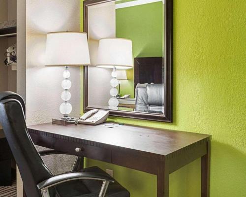 a desk in a room with a mirror and a phone at Quality Suites in Sulphur