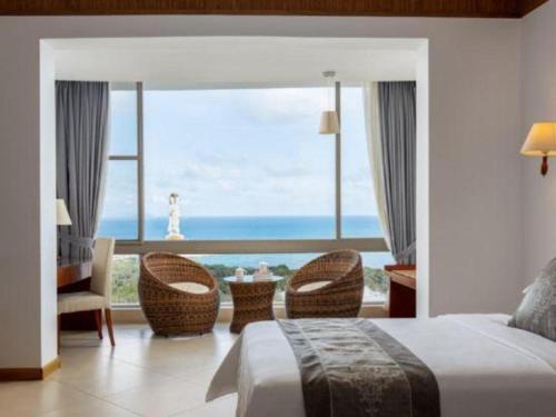 a bedroom with a large window with a view of the ocean at Nanshan Leisure Villas in Shangsimacun