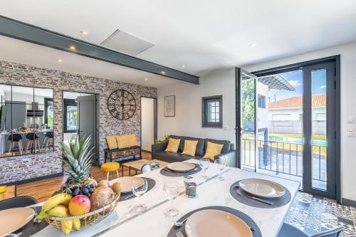 a living room with a table with a bowl of fruit at HOSSEA - Appartements Signature 10 min Océan in Saint-Vincent-de-Tyrosse