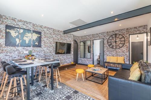 a living room with a brick wall at HOSSEA - Appartements Signature 10 min Océan in Saint-Vincent-de-Tyrosse