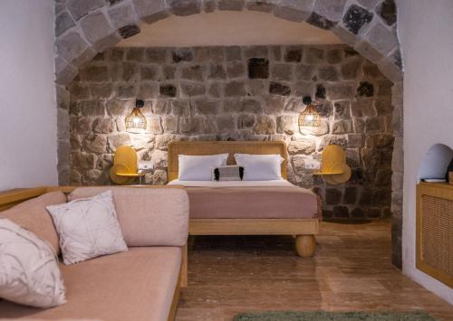 a bedroom with a bed and a couch in front of a stone wall at Cappadocia Naif Hotel - Adults Only in Goreme