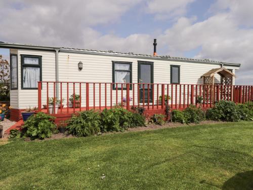 a white house with a red fence and a yard at The Cabin in Lybster
