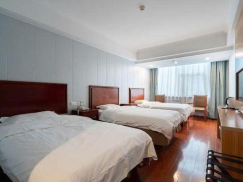 una camera d'albergo con tre letti e una finestra di GreenTree Inn JiangSu WuXi BinHu TaiHu Pearl Development Mansion Business Hotel a Wuxi