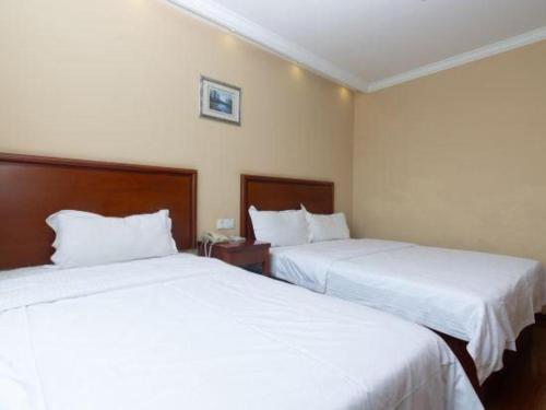 two beds in a hotel room with white sheets at GreenTree Inn Shanghai Hongqiao Airport Huqingping Highway Shell Hotel in Shanghai