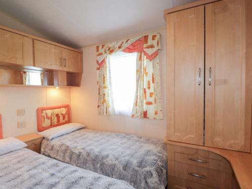 a small bedroom with two beds and a window at The Cabin in Lybster