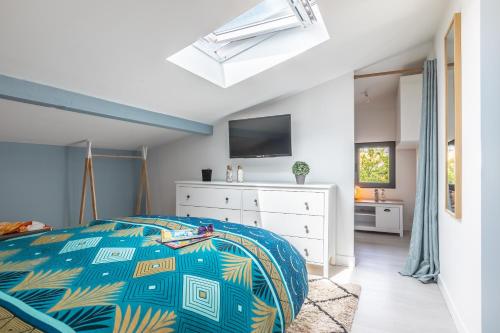 a bedroom with a bed and a tv on the wall at HOSSEA - Appartements Signature 10 min Océan in Saint-Vincent-de-Tyrosse