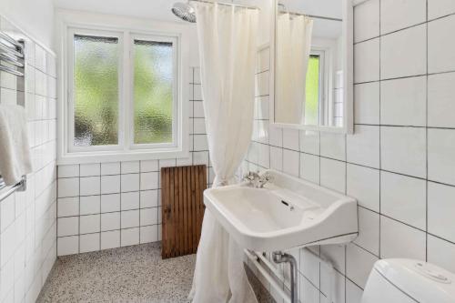 ein weißes Badezimmer mit Waschbecken und Fenster in der Unterkunft Renovated Cottage Near Forest And Beach in Rørvig