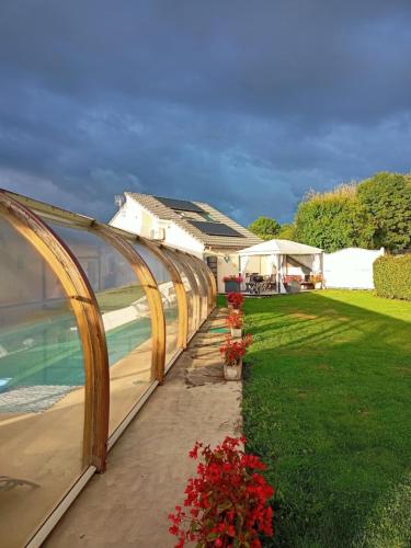a garden with a greenhouse and some red flowers at gîte m et m in Nébouzat