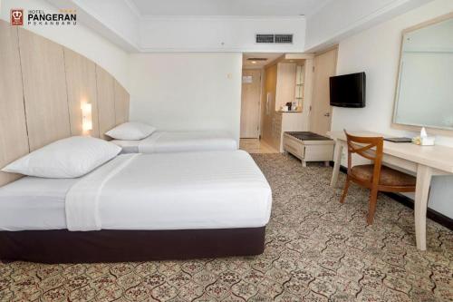 a hotel room with a bed and a desk and a computer at Hotel Pangeran in Pekanbaru