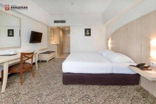 a bedroom with a bed and a desk and a computer at Hotel Pangeran in Pekanbaru