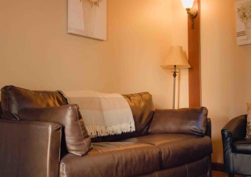 a brown leather couch in a living room with a lamp at Cabernet House, an Old World Inn in Napa