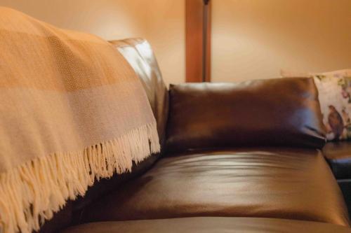 a brown leather couch with a blanket on it at Cabernet House, an Old World Inn in Napa