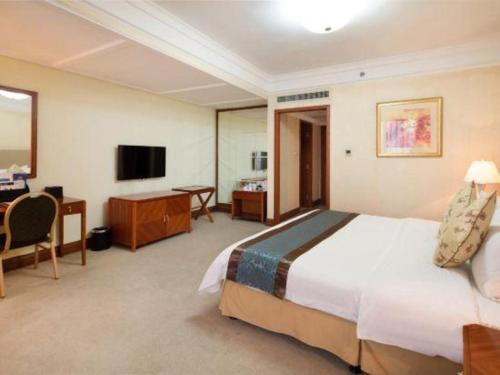a hotel room with a large bed and a desk at Changshu Jinling Tianming Grand Hotel in Suzhou